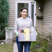 Woman carrying a box full of hazardous waste out of house. 