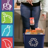 Woman throwing a peanut butter jar into a blue recycling bin. 
