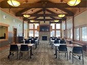 Photo of the Great Room at the Nordic Center, with chairs and tables set up facing a fireplace with a TV mounted over it.