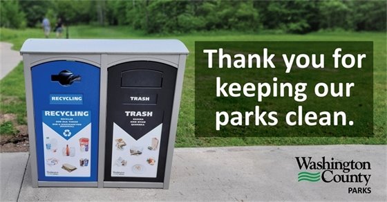 Dual-bin waste station with separate compartments labeled "RECYCLING" and "TRASH" in a park setting. The recycling side is blue with symbols of recyclable items, and the trash side is black with images of non-recyclable waste. A banner on the station reads, "Thank you for keeping our parks clean," and includes the logo of Washington County Parks.