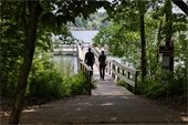 Two people and a small child walking on a pier towards the water.